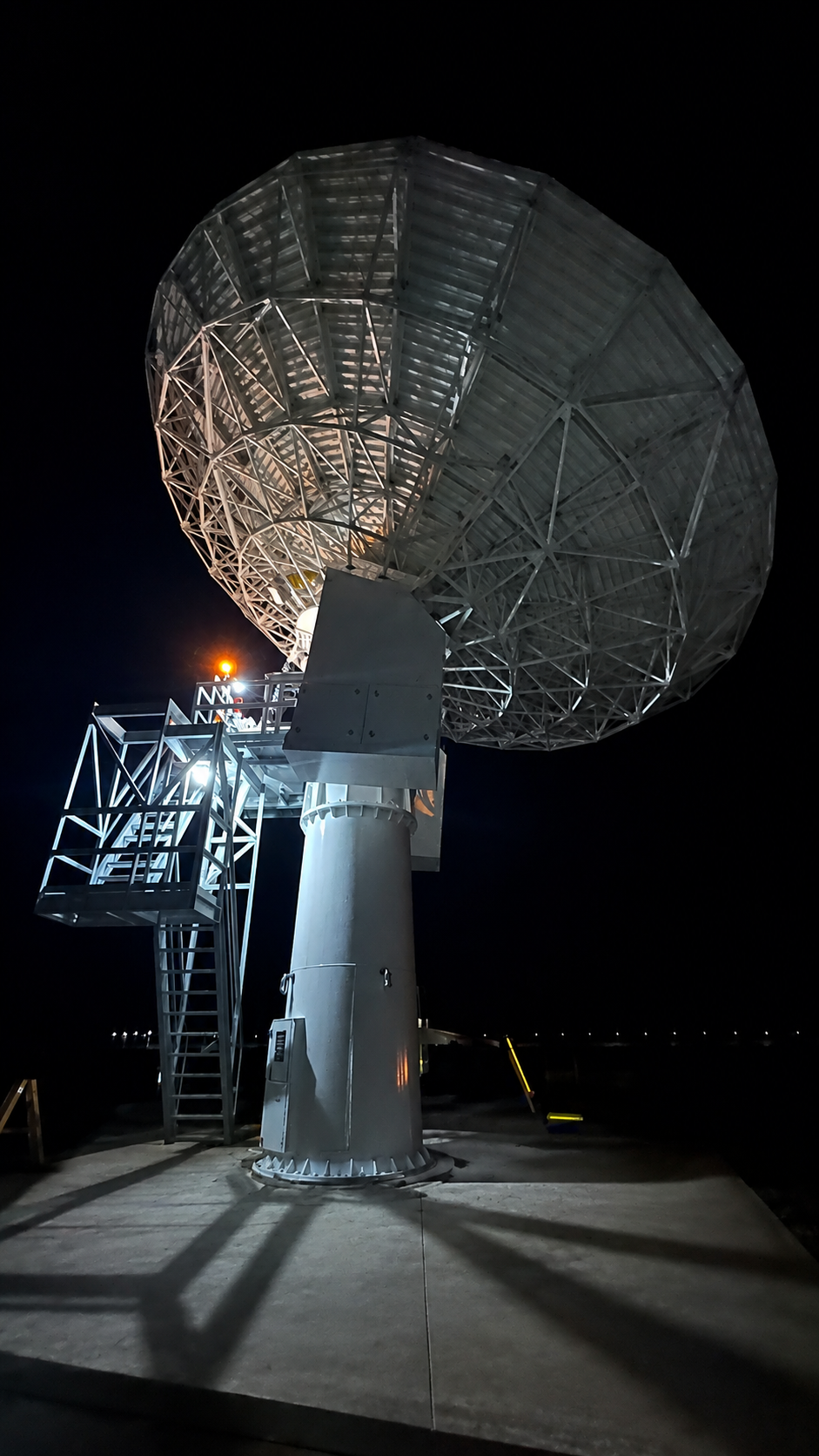 Large earth-station antenna illuminated during nighttime field work
